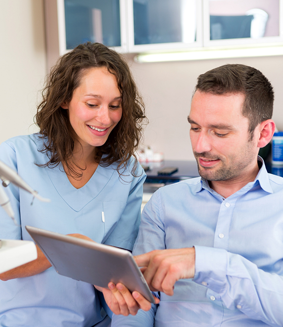 Dental team member showing a tablet to a patient in the dental chair