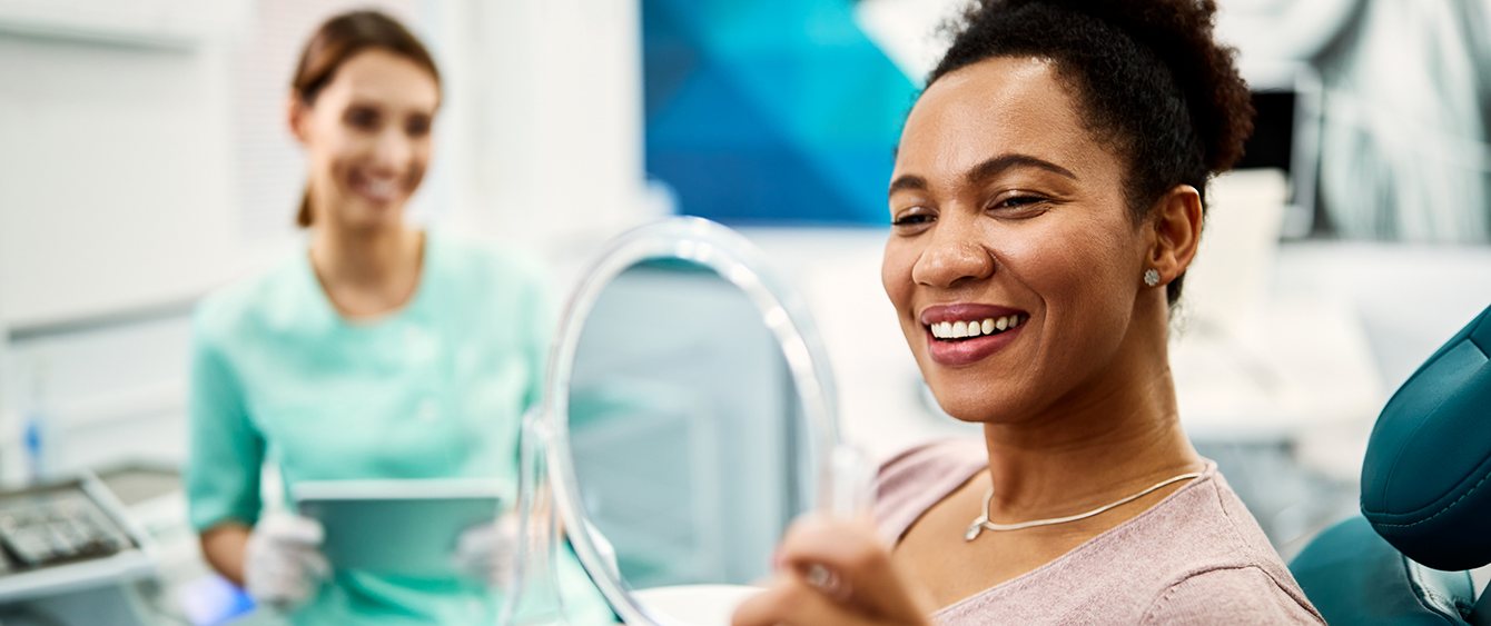 Dental patient admiring her smile in a mirror after cosmetic dentistry in Jacksonville