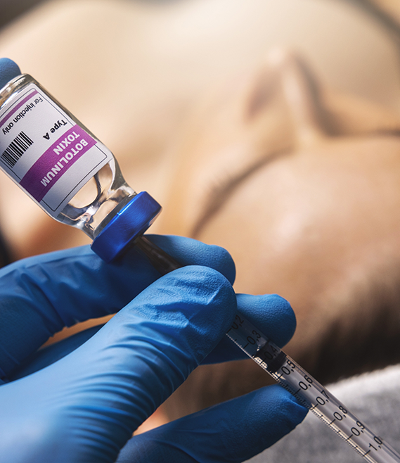 Medical professional drawing a syringe from a vial of clear liquid