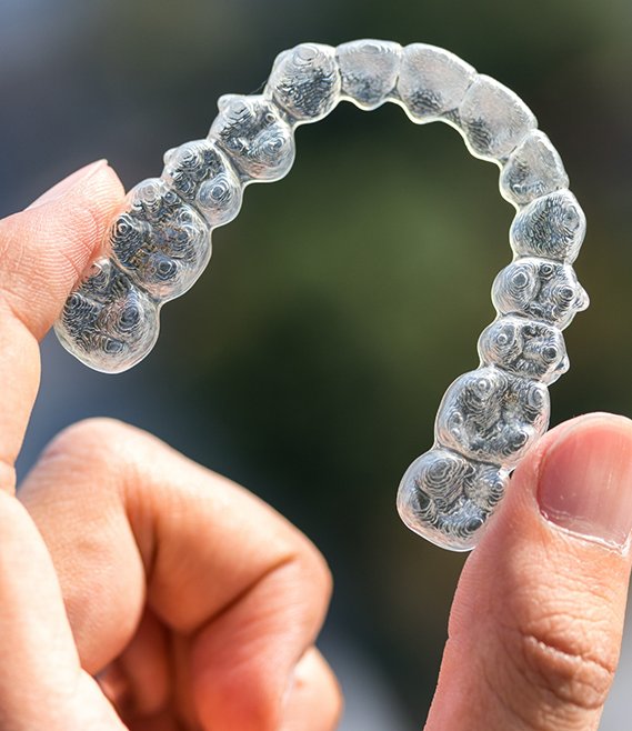 Hand holding an Invisalign clear aligner