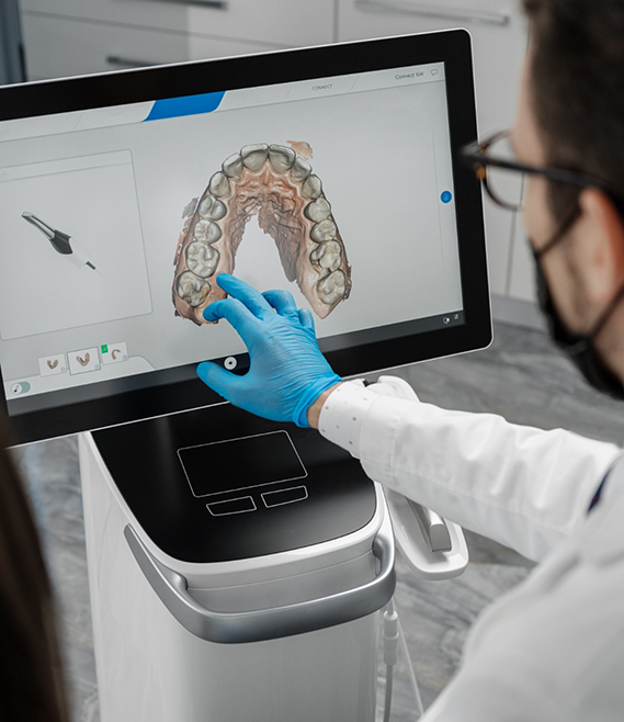 Dentist touching a screen showing digital impressions of a row of teeth