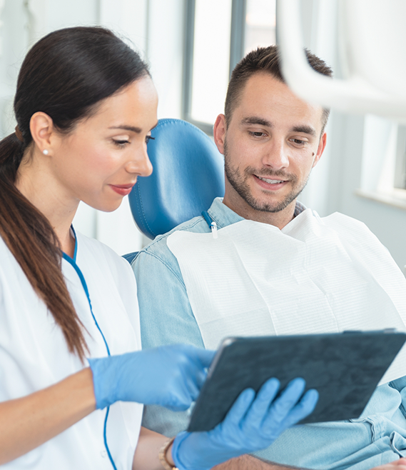 Dental team member showing a tablet to a man in the dental chair