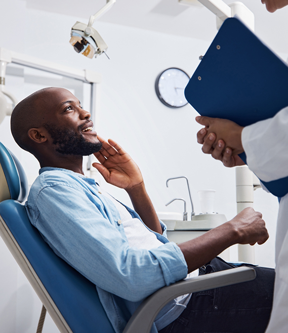 Man in dental chair smiling while looking up at his dentist