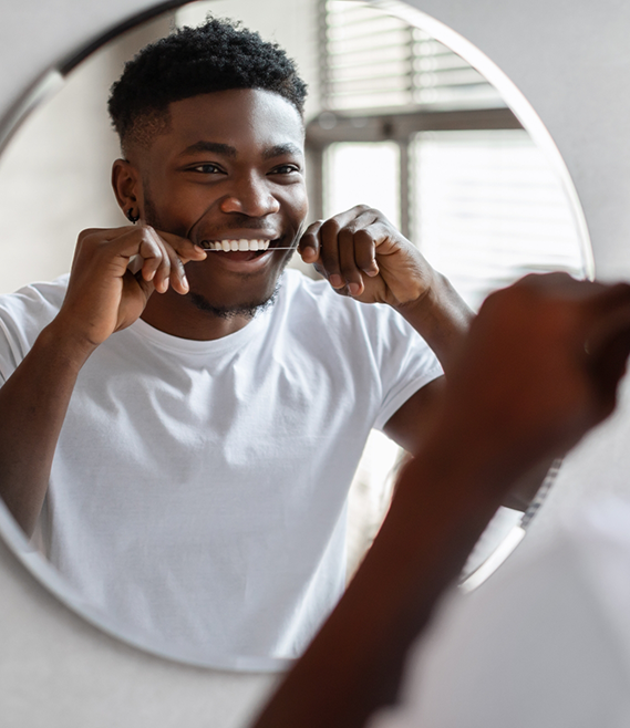 Man flossing his teeth in front of a mirror