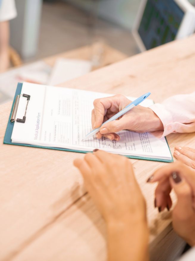 Dental patient filling out paperwork on a clipboard