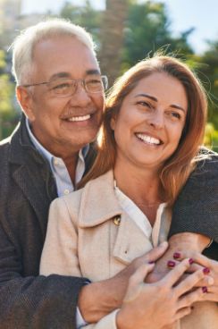 Man hugging woman from behind outdoors on sunny day