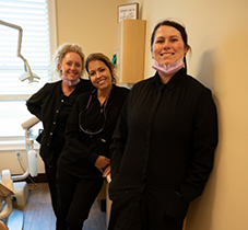 Three dental team members smiling in dental office