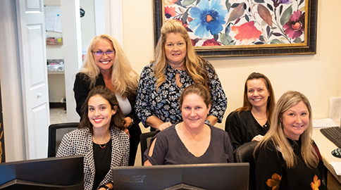 Several dental team members smiling at front desk