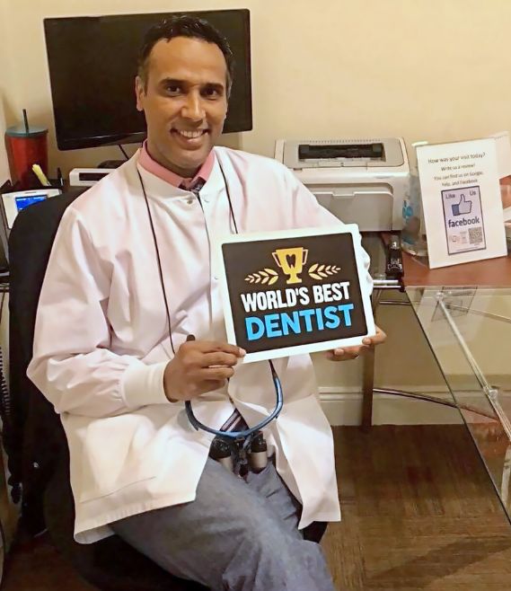 Doctor Waheed holding a paper that says worlds best dentist