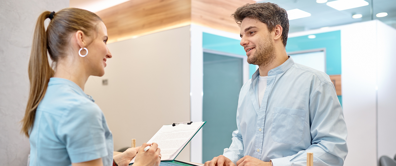 Dental team member holding a clipboard while talking to a dental patient in Jacksonville