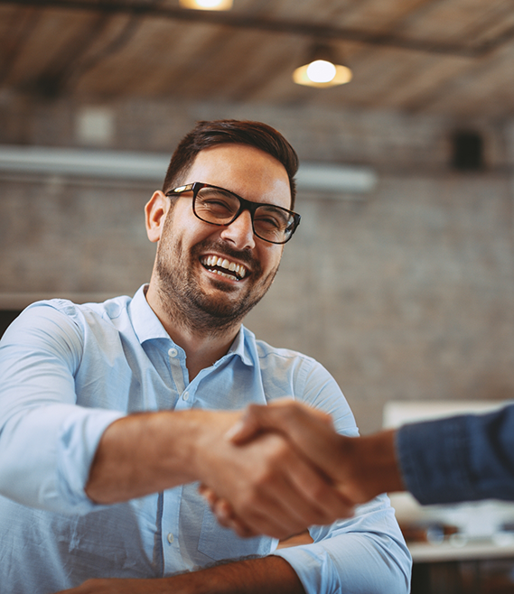 Man grinning while shaking hands with someone out of frame