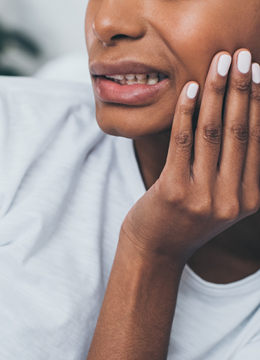 Person wincing in pain and touching the side of their jaw