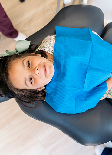 Young girl in dental chair looking up toward the camera