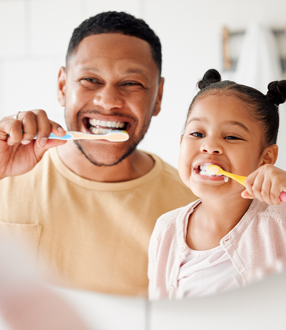 Father and daughter brushing their teeth together