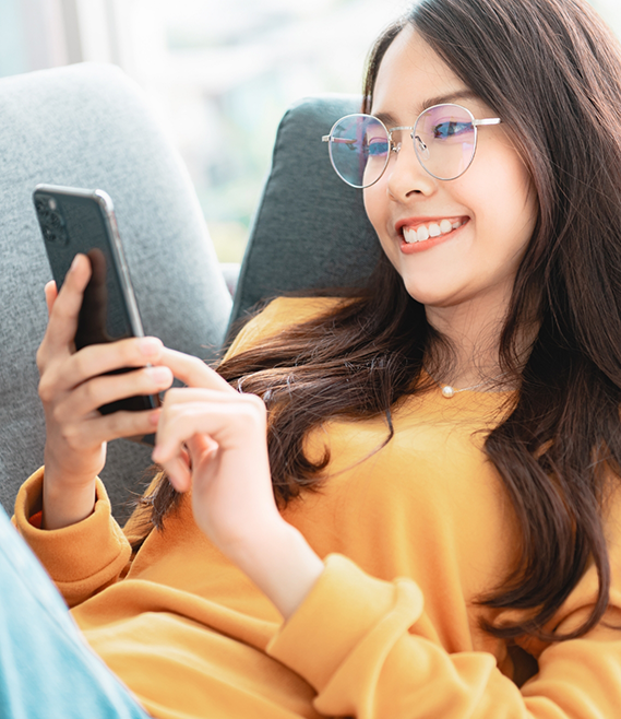 Young woman smiling while scrolling on her phone