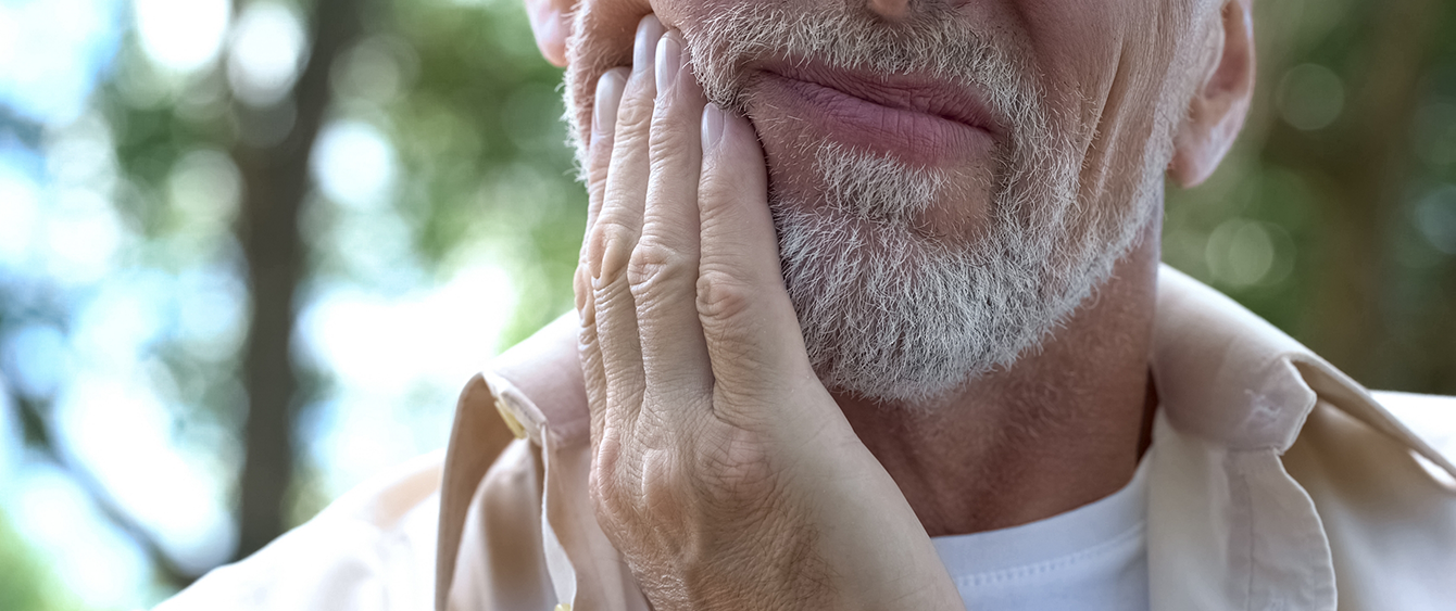 Man holding the side of his face in pain needing root canal treatment