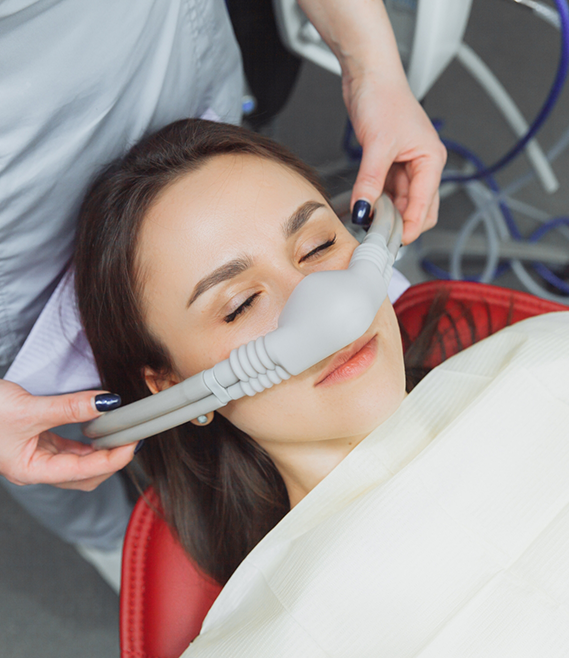 Woman relaxing in dental chair with nitrous oxide mask over her nose