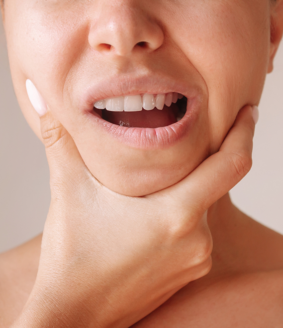 Close up of a person touching the sides of their jaw in pain